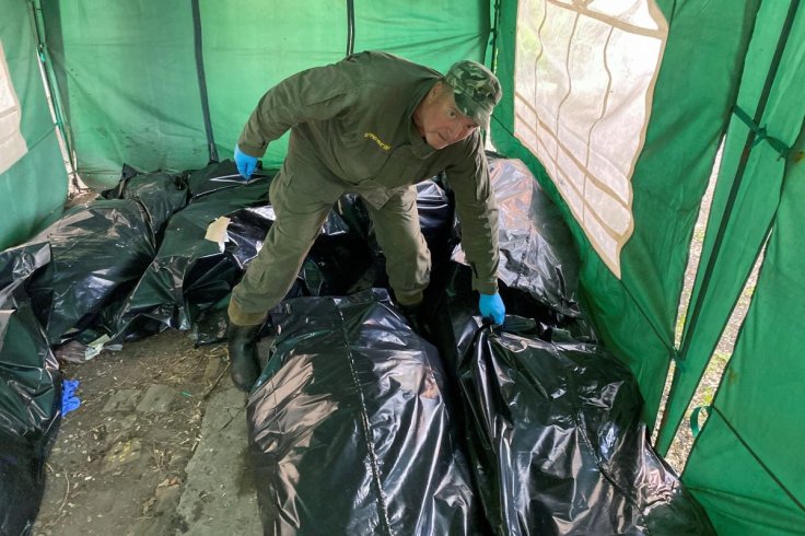 A ritual worker picks up the body of a killed Russian soldier before loading them to a refrigerated rail car, as Russia's attack on Ukraine continues, at a compound of a morgue in Kharkiv, Ukraine May 22, 2022.