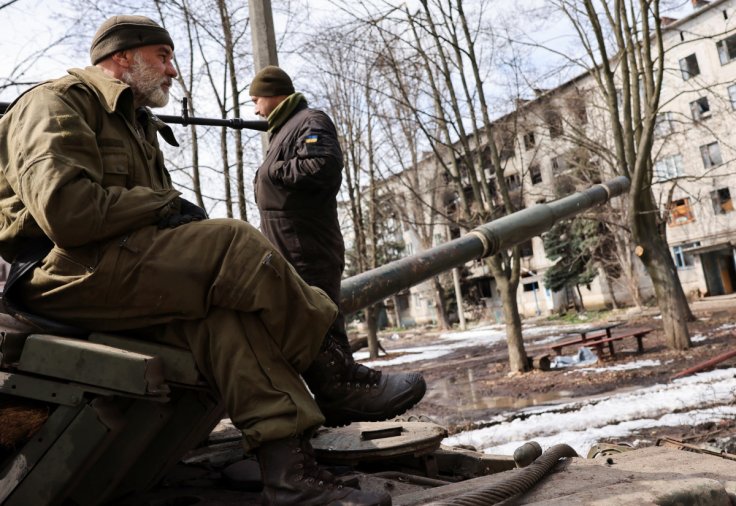 Ukrainian servicemen stand atop a tank, near the bombed-out eastern city of Bakhmut